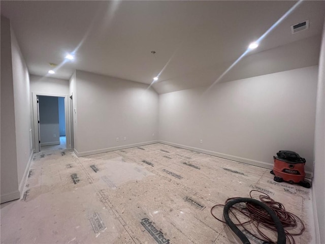 unfurnished room featuring visible vents, baseboards, and vaulted ceiling