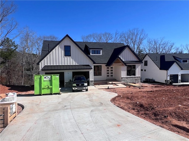 modern farmhouse with concrete driveway, board and batten siding, and roof with shingles