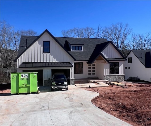 modern farmhouse with driveway, a garage, a shingled roof, stone siding, and board and batten siding