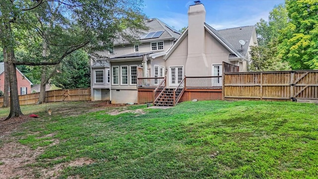 rear view of property featuring a fenced backyard, a yard, a wooden deck, a gate, and a chimney