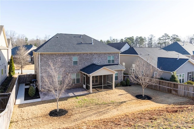 rear view of house with a patio area, brick siding, a fenced backyard, and roof with shingles