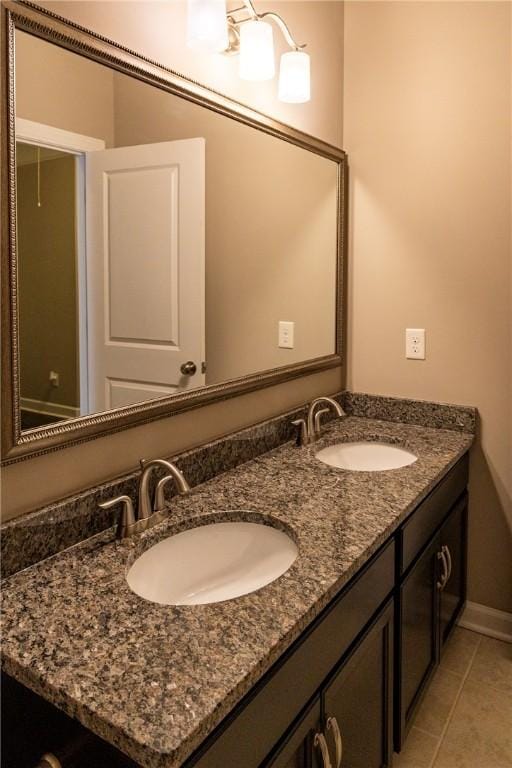 bathroom with double vanity, baseboards, a sink, and tile patterned floors