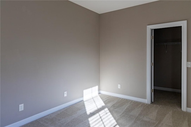 unfurnished bedroom with a closet, carpet, a walk in closet, and baseboards