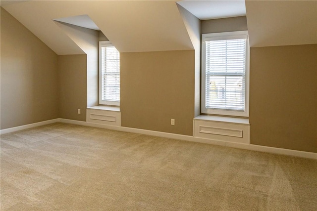 bonus room with light carpet, baseboards, and vaulted ceiling