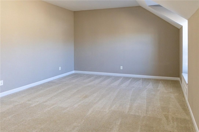 bonus room with lofted ceiling, light colored carpet, and baseboards