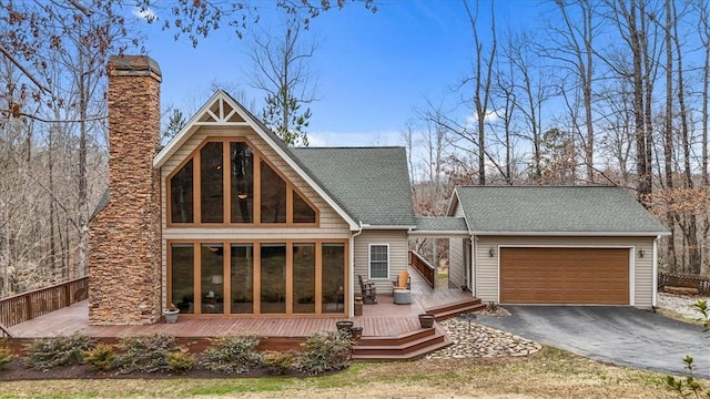 rear view of house with aphalt driveway, a shingled roof, a sunroom, a garage, and a wooden deck