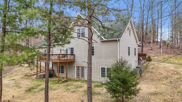 back of house with roof with shingles and a wooden deck