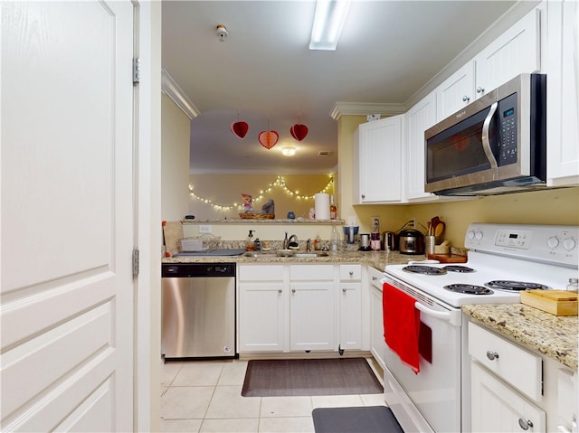 kitchen with appliances with stainless steel finishes, white cabinets, a sink, and light tile patterned floors