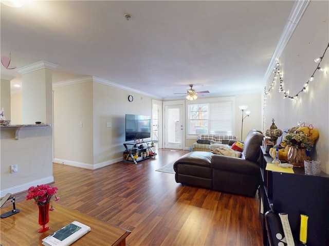 living area with baseboards, wood finished floors, a ceiling fan, and crown molding