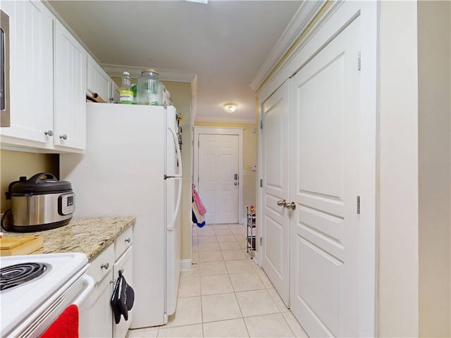 kitchen with white cabinets, ornamental molding, freestanding refrigerator, light stone countertops, and light tile patterned flooring