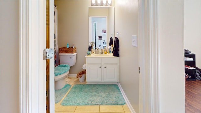 bathroom featuring baseboards, vanity, toilet, and tile patterned floors