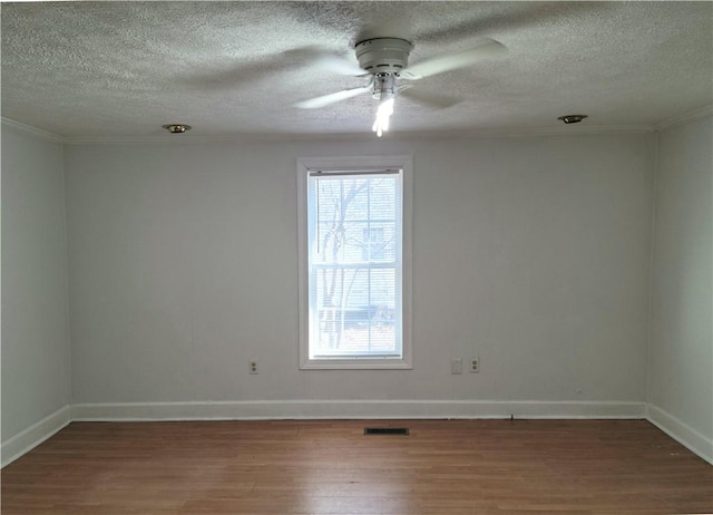 unfurnished room with a ceiling fan, visible vents, baseboards, and wood finished floors