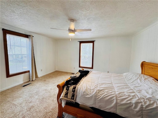 bedroom with a textured ceiling, carpet floors, visible vents, and a ceiling fan