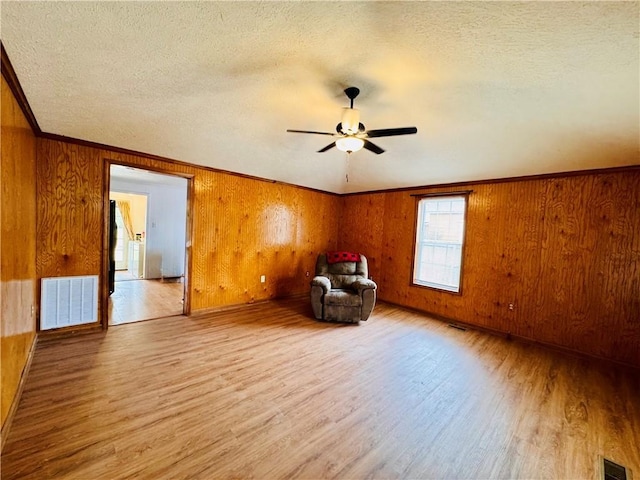 unfurnished room with a textured ceiling, wood finished floors, and visible vents