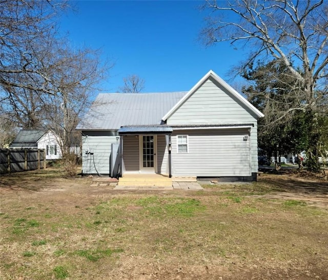 back of house featuring metal roof, a yard, and fence