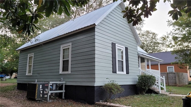 view of side of property featuring central AC unit, fence, and metal roof