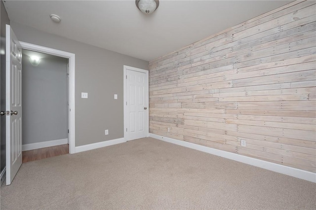 unfurnished bedroom featuring a closet, baseboards, carpet, and wood walls