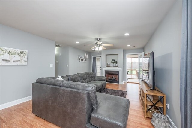 living room featuring recessed lighting, light wood-type flooring, baseboards, and a fireplace