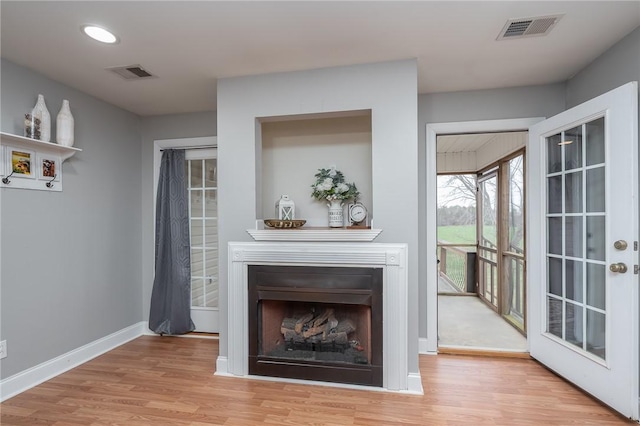 unfurnished living room featuring visible vents, a fireplace, baseboards, and wood finished floors