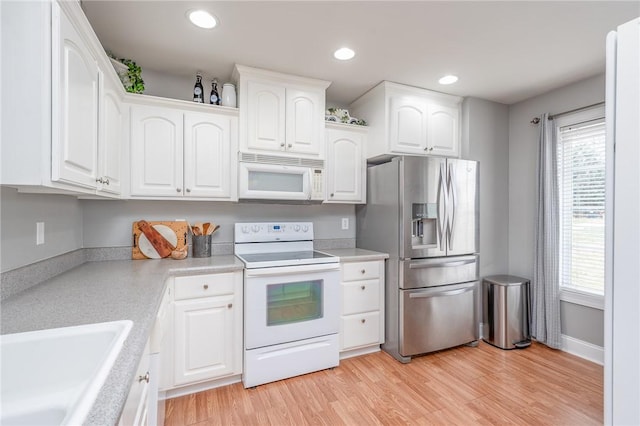 kitchen featuring light wood-type flooring, white appliances, plenty of natural light, and white cabinetry