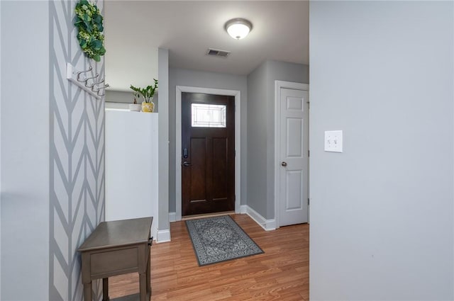 foyer entrance with visible vents, baseboards, and light wood-style flooring