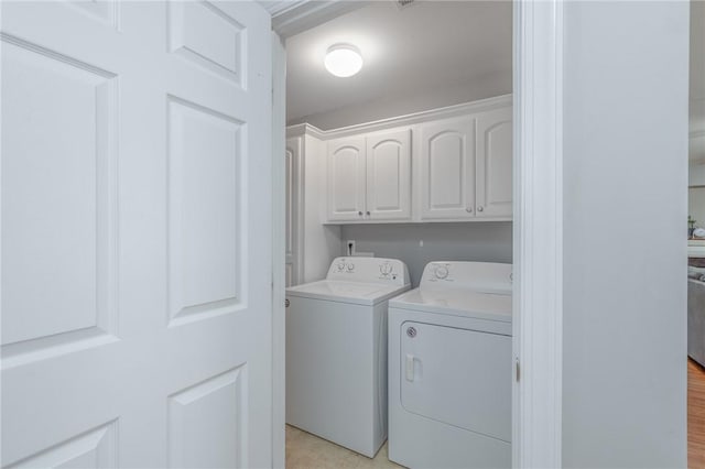 clothes washing area featuring cabinet space and separate washer and dryer