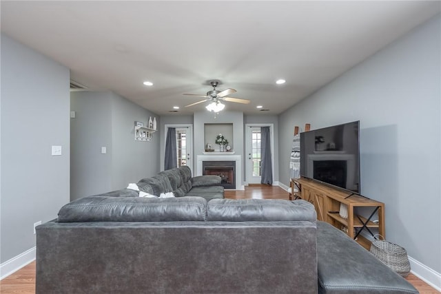 living room featuring ceiling fan, baseboards, recessed lighting, a fireplace, and wood finished floors