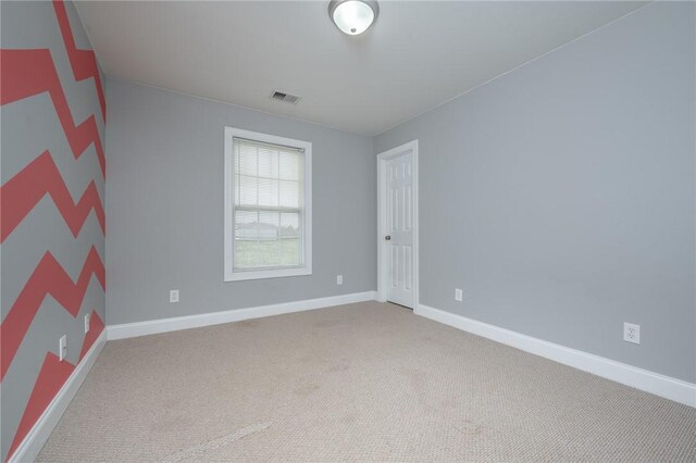 empty room with carpet flooring, baseboards, and visible vents