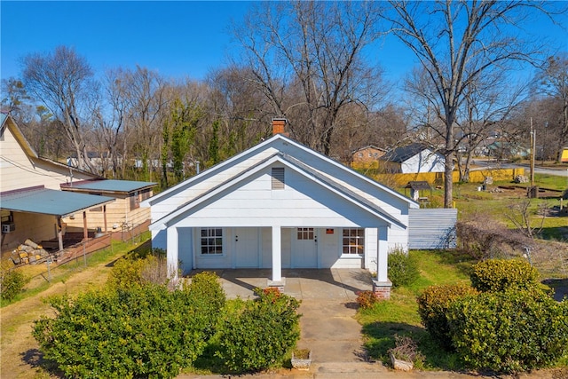 exterior space featuring covered porch, a chimney, and fence