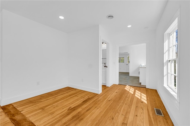 spare room with plenty of natural light, light wood-style floors, and visible vents