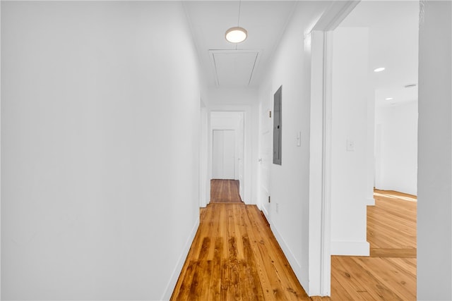 hall with attic access, electric panel, wood finished floors, and baseboards