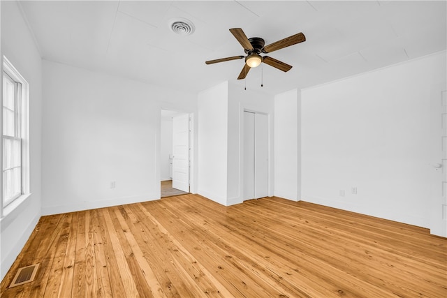 empty room with baseboards, visible vents, light wood finished floors, and ceiling fan