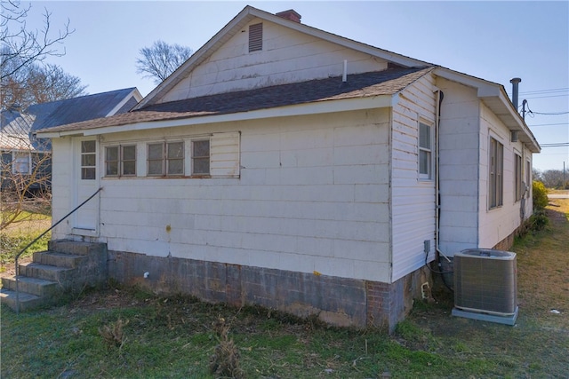 view of home's exterior featuring entry steps, cooling unit, and roof with shingles