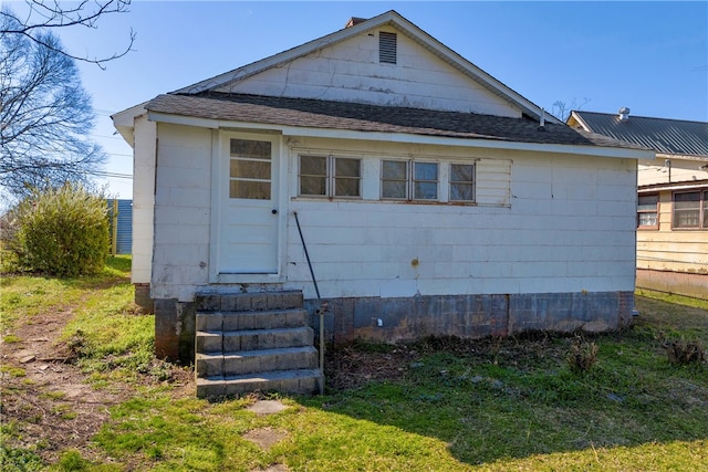 exterior space featuring entry steps and a shingled roof