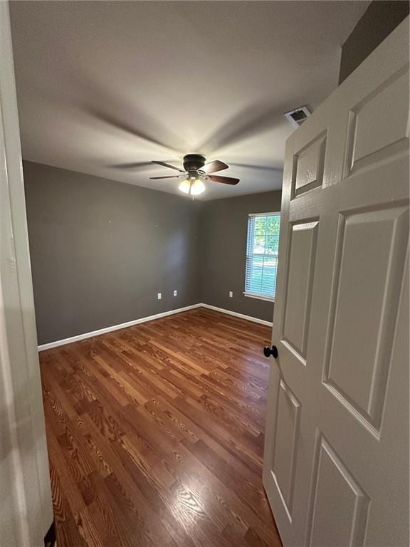 unfurnished bedroom with visible vents, baseboards, dark wood-type flooring, and a ceiling fan