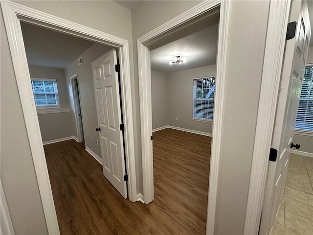 corridor with visible vents, wood finished floors, and baseboards