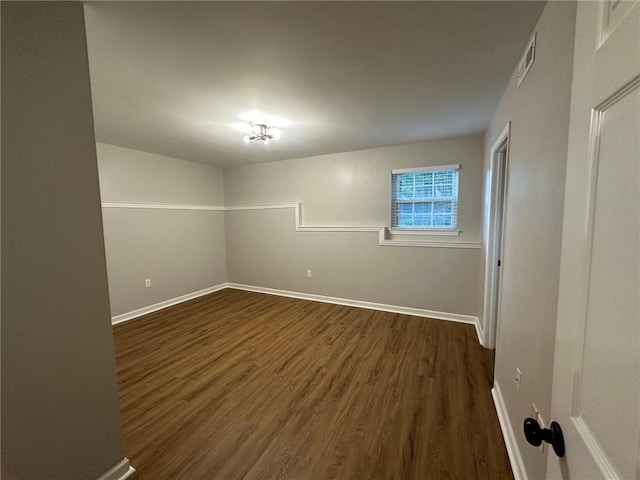 empty room with visible vents, baseboards, and dark wood-type flooring