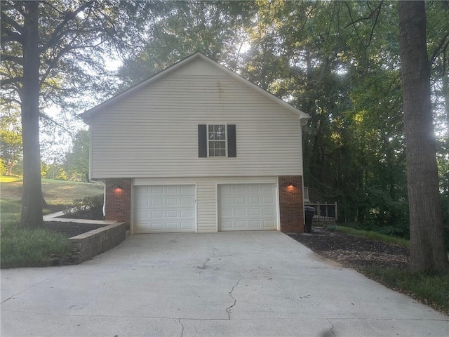 view of side of home with an attached garage, brick siding, and driveway