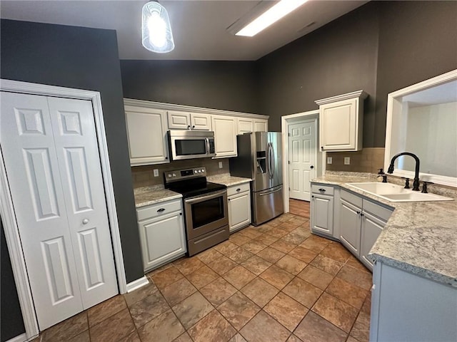 kitchen with decorative light fixtures, light countertops, decorative backsplash, appliances with stainless steel finishes, and a sink