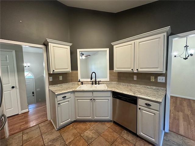 kitchen featuring wood finished floors, a sink, decorative backsplash, dishwasher, and a notable chandelier