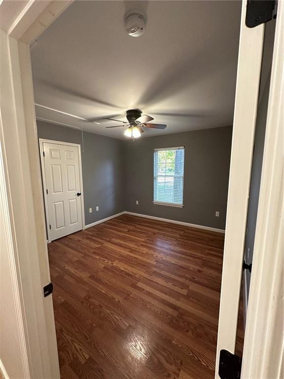 unfurnished bedroom with a ceiling fan, dark wood-style floors, and baseboards