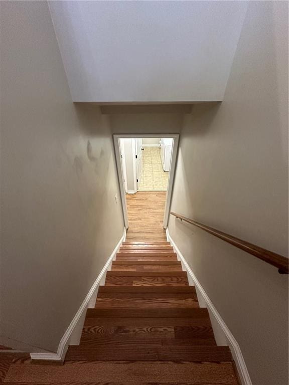 staircase featuring baseboards and wood finished floors