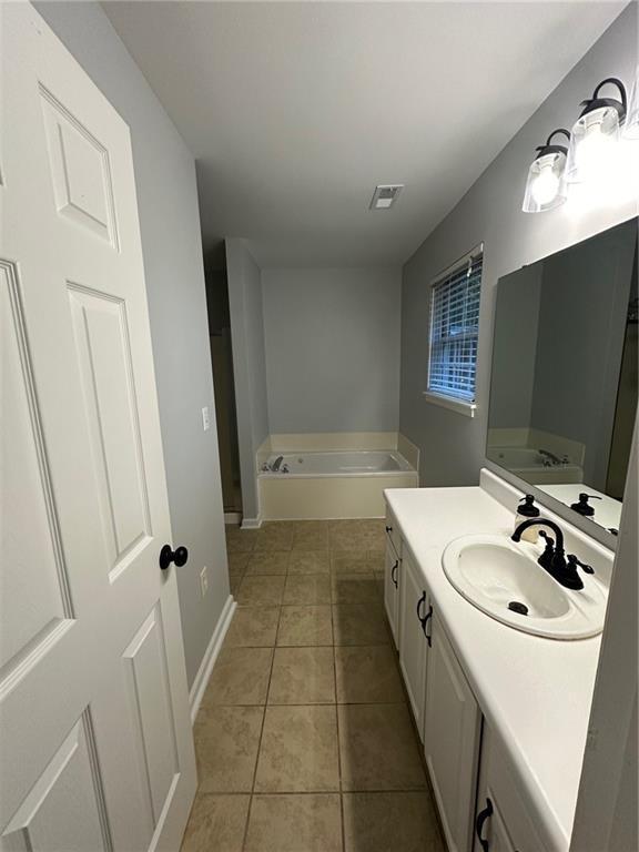 bathroom featuring vanity, a garden tub, baseboards, visible vents, and tile patterned floors