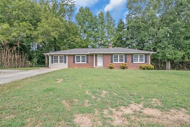 ranch-style house featuring brick siding, concrete driveway, a chimney, and a front lawn