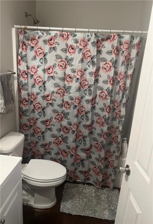 full bath featuring a shower with shower curtain, toilet, and vanity