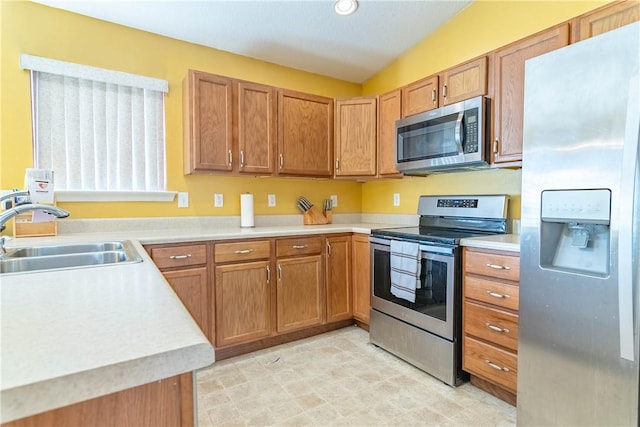 kitchen featuring brown cabinets, a sink, recessed lighting, stainless steel appliances, and light countertops