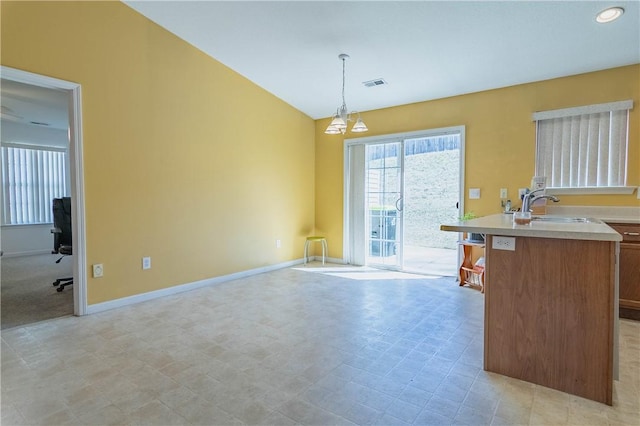 kitchen with visible vents, baseboards, light countertops, hanging light fixtures, and a sink