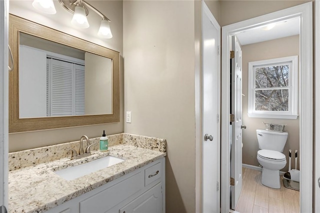 bathroom with vanity, toilet, and baseboards