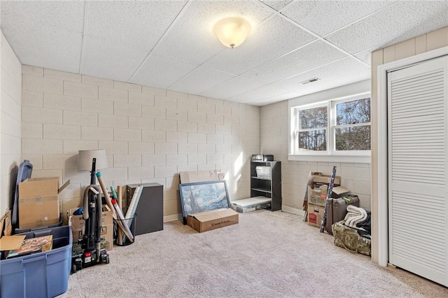 interior space featuring a drop ceiling, visible vents, carpet, and concrete block wall