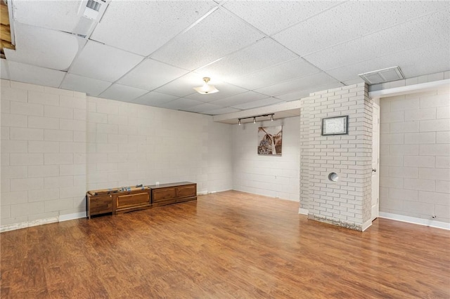 finished basement featuring a paneled ceiling, wood finished floors, and concrete block wall